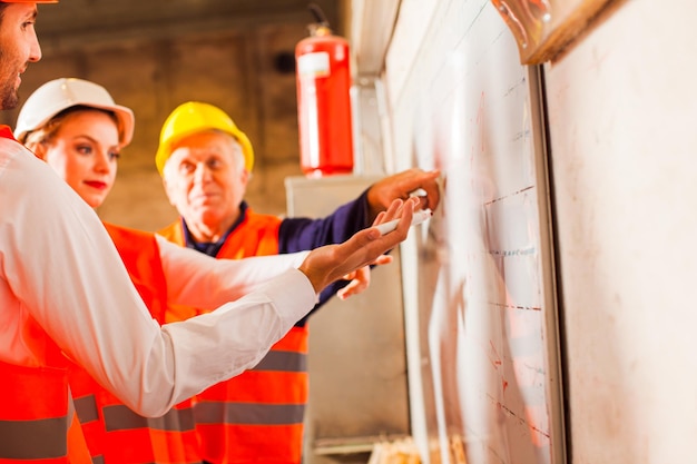 Schwierige Fragen diskutieren die drei Arbeiter in Arbeitskleidung als nächstes an Bord