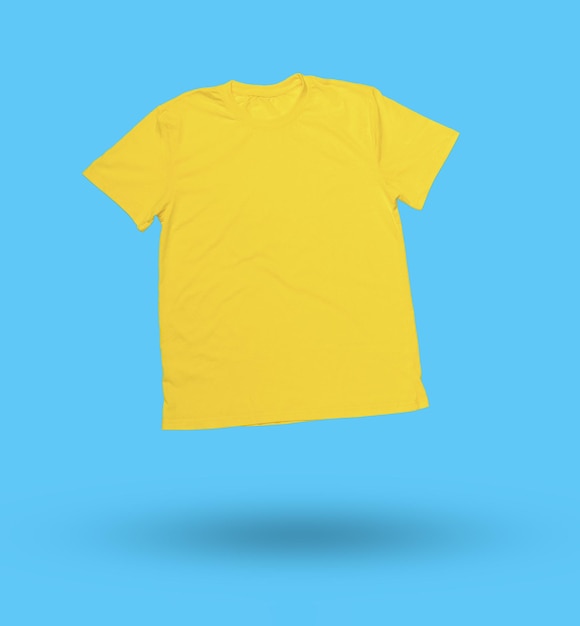 Schwimmendes gelbes T-Shirt auf hellblauem Hintergrund Minimalistische Produktfotografie für Kleidung und Mode