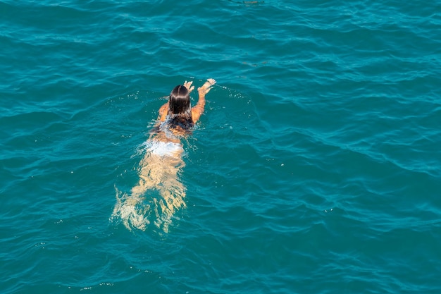 Schwimmendes Mädchen in weißen Badeanzügen im blauen Meer