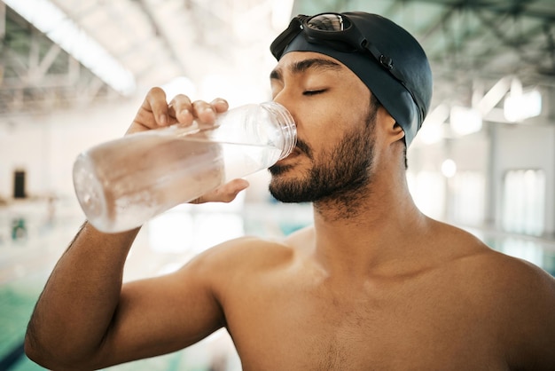 Schwimmer und Trinkwasser für Flüssigkeitszufuhr oder Trainingstraining im Hallenbad Aktive und durstige männliche Person oder Sportler mit Mineralgetränk für nachhaltige Fitness oder Cardio