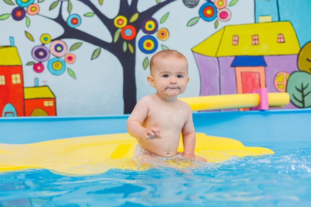 Schwimmunterricht für Kinder Ein kleiner Junge lernt im Babybecken schwimmen. Entwicklung der Kinder Erster Schwimmunterricht für Kinder
