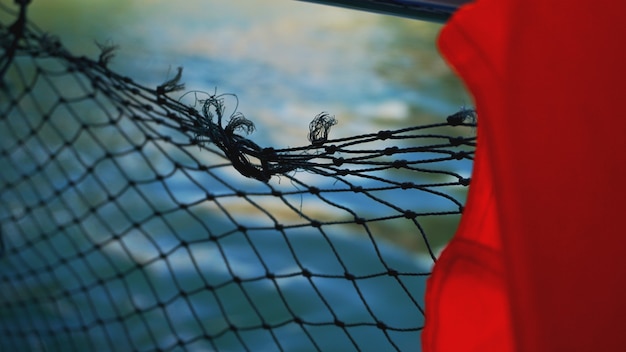 Schwimmweste und Netz auf dem Boot. Sicherheitsnetz auf dem Boot. Seile auf dem Boot. Sicherheitsseile und blaues Meer. Wellen auf dem Meer und Sicherheitsnetz.