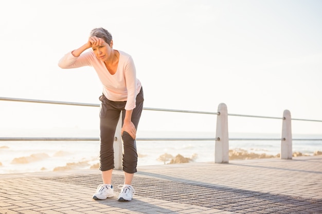 Schwitzende sportliche Frau, die an der Promenade stillsteht