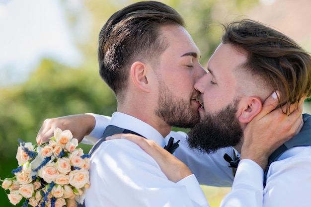 Schwuler Mann mit Partner am Hochzeitstag. Schwuler Kuss bei der Hochzeit. Schwules Paar küsst sich zärtlich aus nächster Nähe