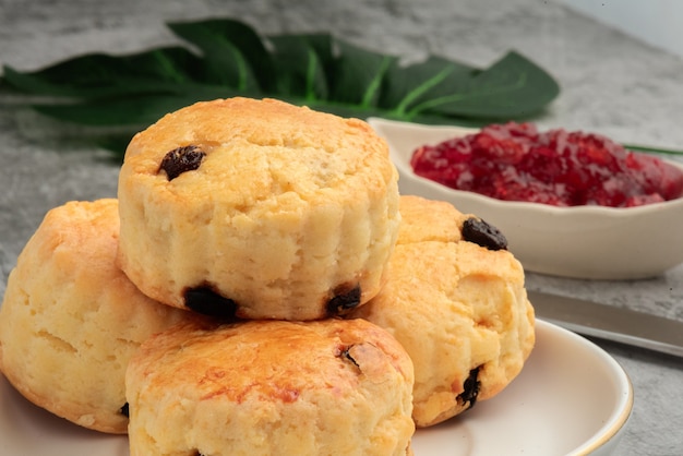 Scone em prato branco e geléia de morango no fundo do cemen