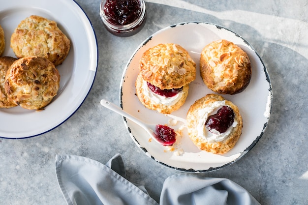 Scones británicos tradicionales con crema cuajada, mermelada de frambuesa