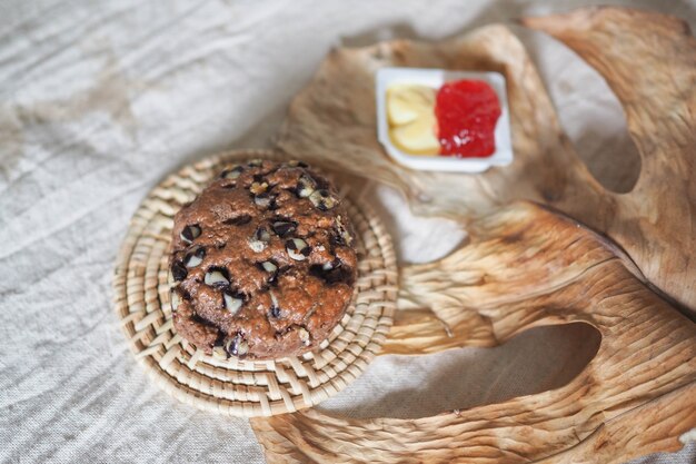 Foto scones de chocolate com geléia de morango e creme de leite com folhas secas na superfície do tecido