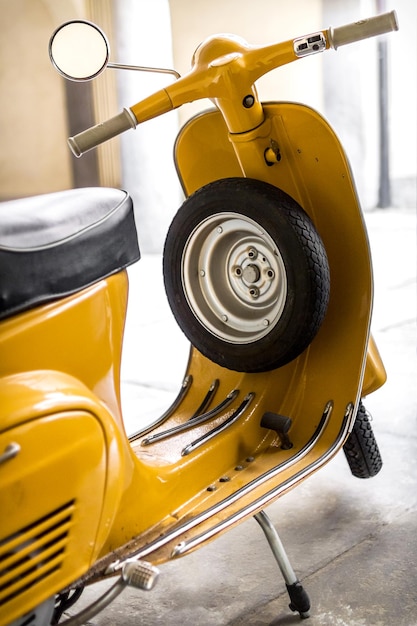 Foto scooter amarillo estacionado con neumático de repuesto