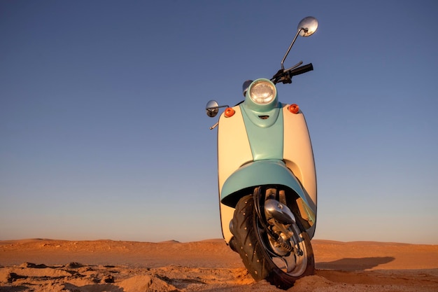 Foto scooter azul retrô ao pôr do sol na areia dourada do deserto do namib