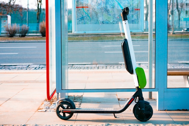 Scooter eléctrico está parado cerca de la parada de autobús público. Scooter público para alquilar