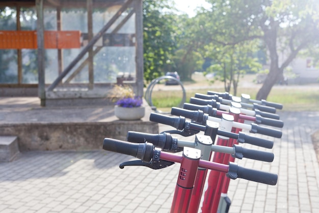 Foto scooter eléctrico en la ranura de estacionamiento fila de transporte urbano listo para montar bicicletas con acumuladores en el pavimento en el parque en estonia