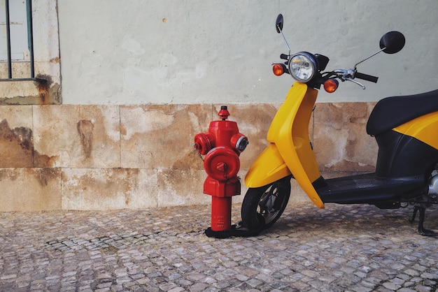 Scooter de motor junto a la boca de incendios en el sendero junto a la pared