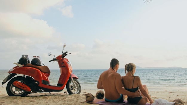 Scooter Roadtrip Schönes Paar auf rotem Motorrad in weißer Kleidung am Sandstrand