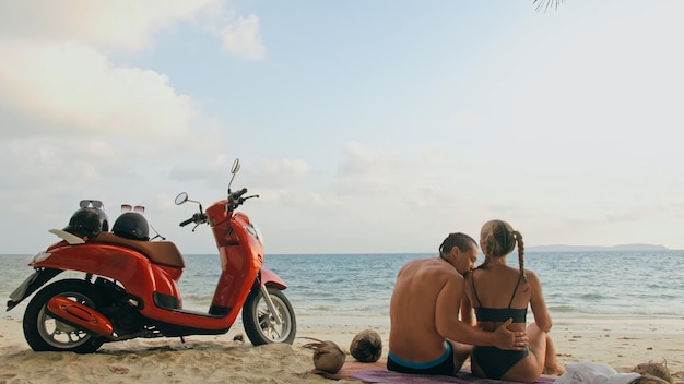 Scooter Roadtrip Schönes Paar auf rotem Motorrad in weißer Kleidung am Sandstrand