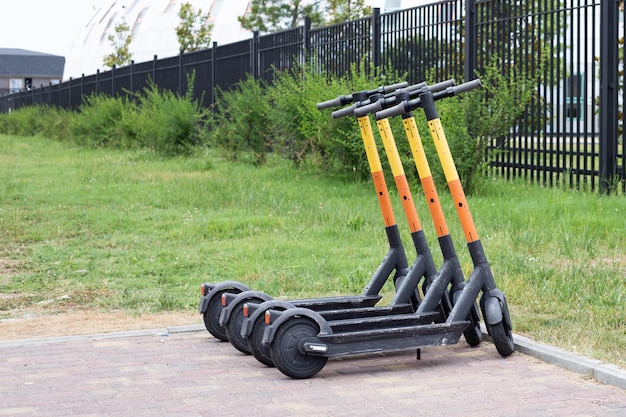 Scooters eléctricos en fila en el estacionamiento. Sistema de alquiler de bicicletas urbanas, patinetes públicos en la calle.