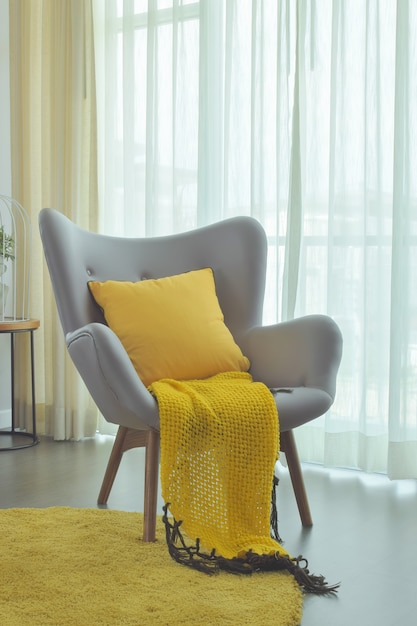 Foto scraft amarillo y almohada amarilla en el sillón fácil de color gris en la sala de estar