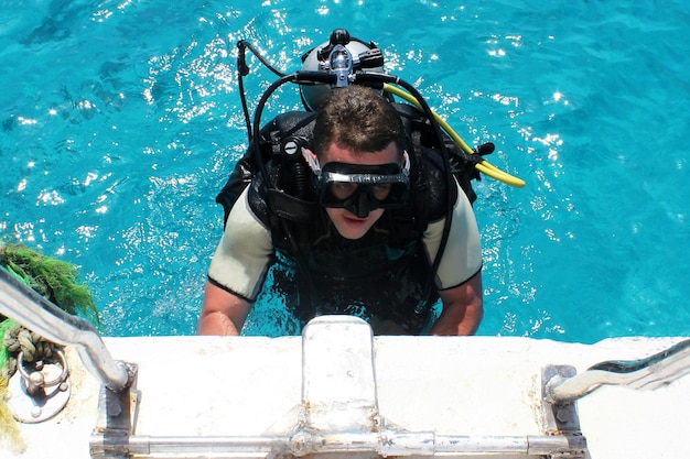 Scuba Diver klettert aus dem Wasser auf die Yacht Unterwassertauchen