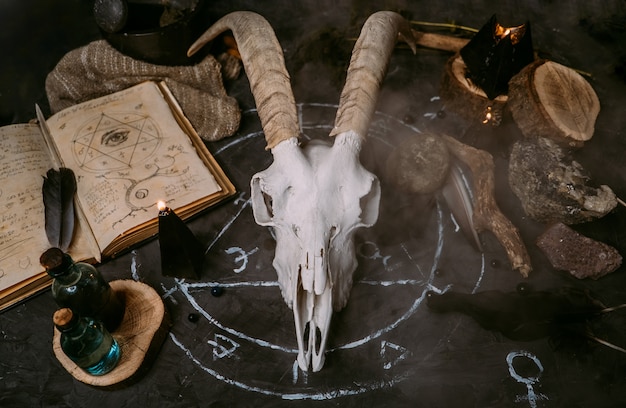 Scull de cabra branca com chifres, livro antigo aberto com feitiços, runas, velas pretas e ervas na mesa de bruxa.
