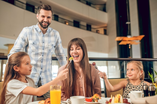 Se divertindo. Família sorridente sentada à mesa e se divertindo