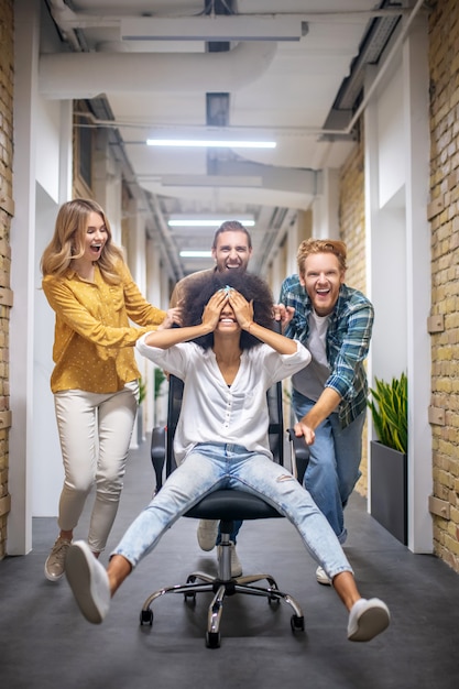 Foto se divertindo. grupo de jovens na cadeira no corredor do escritório após um bom dia