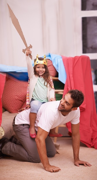 Se divertindo muito Uma menina bonitinha vestida de princesa enquanto brincava em casa com o pai