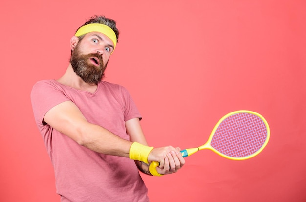 Se divertindo Tênis lazer ativo Jogador de tênis moda vintage Tênis esporte e entretenimento Atleta hipster segurar a raquete de tênis na mão fundo vermelho Homem barbudo hipster usar roupa esportiva