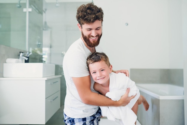 Se divertindo um pouco secando Foto recortada de um jovem pai bonito secando seu adorável filho depois de um banho no banheiro em casa