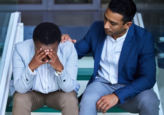 Sé fuerte cuando todo parece ir mal Captura de un joven consolando a su colega en el trabajo