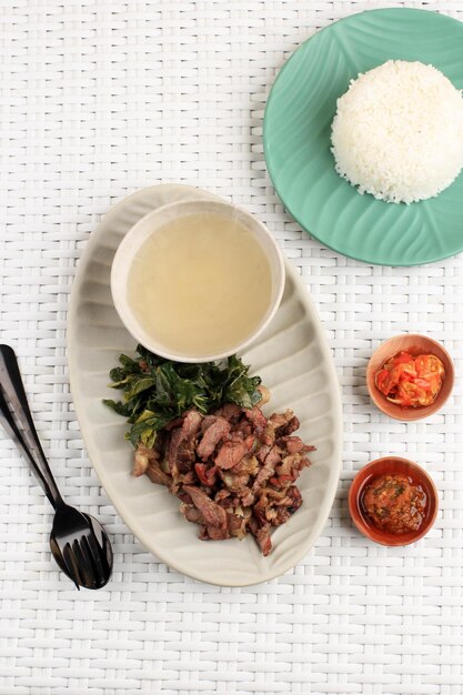 Se'i Sapi oder Beef Sei ist indonesisches traditionelles geräuchertes Rindfleisch, das mit gekochten Maniokblättern und Sambal Luat oder Sambal Matah serviert wird. Typisches Essen aus Nusa Tenggara, Indonesien. Ansicht von oben