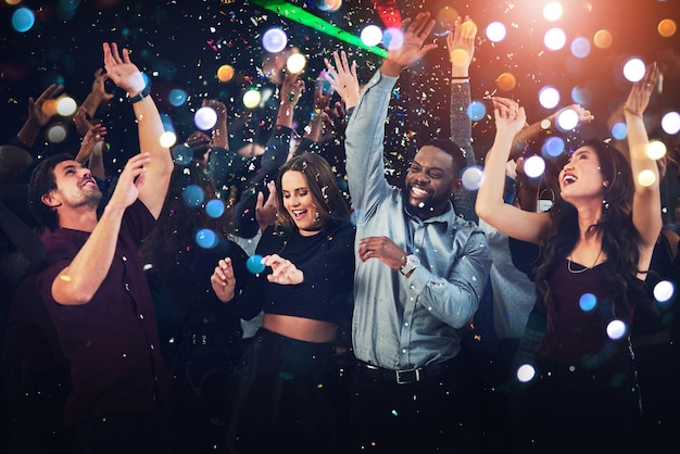 Se uma festa for lançada, pegue-a Foto recortada de um grupo diversificado de jovens amigos dançando em uma festa à noite
