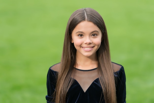 Sea grandioso todos los días. Niño feliz sonrisa hierba verde. Mirada de belleza de niña linda. Peluquería. Moda y estilo. Puericultura y niñez. Día del Niño.