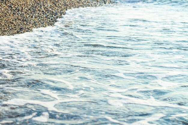 Sea surf en una playa de guijarros al amanecer o al atardecer. Marina. Enfoque estrecho