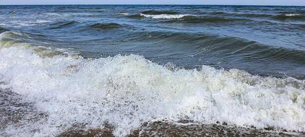 Seascape. Cor azul da água, ondas espumando na costa. Foco seletivo.