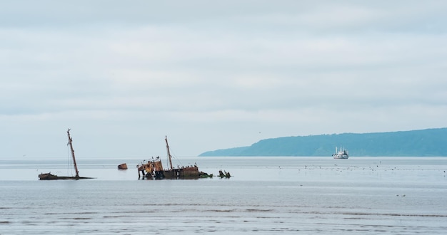 Seascape con un naufragio en primer plano y un pequeño barco pesquero en el mar en el fondo