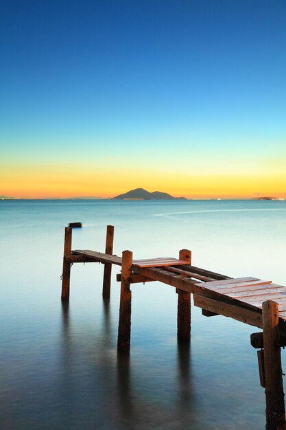 Seascape con puesta de sol y puente de madera.