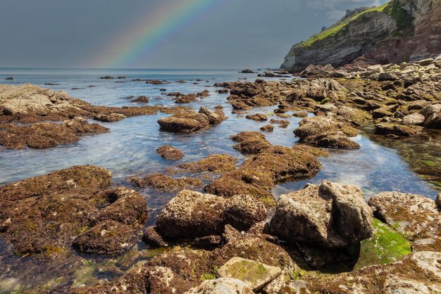 Seascape rochoso de cores vibrantes e arco-íris no fundo