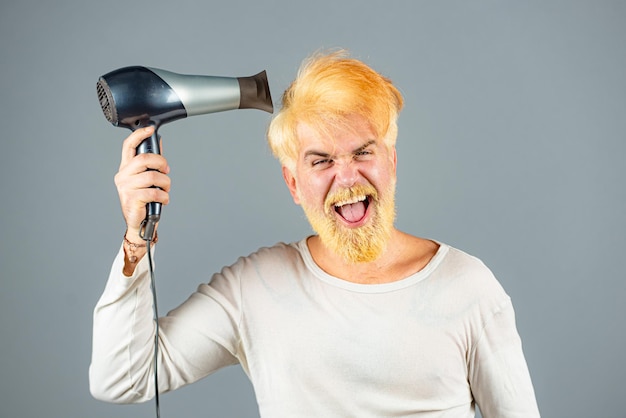 Secador de pelo rubio para un hombre rubio barbudo hipster con secador de pelo o fen