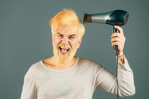 Secador de pelo rubio para un hombre rubio barbudo hipster con secador de pelo o fen