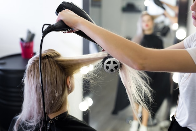 Secagem de cabelo loiro comprido com secador de cabelo e escova redonda