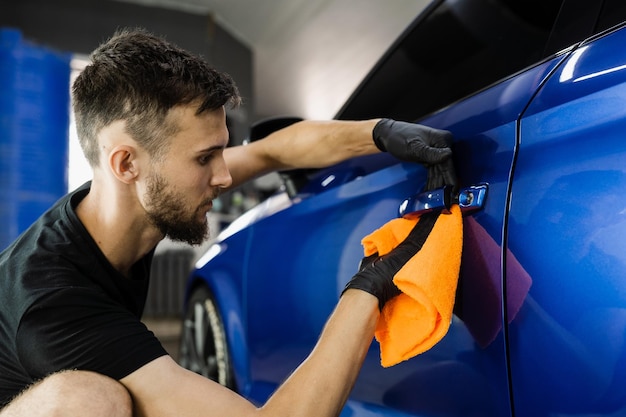 Secagem de carro manual com microfibra no detalhamento do serviço automático Trabalhador de limpeza de carro seco após lavar o automóvel