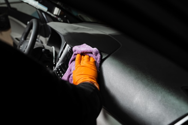 Secagem manual do interior do carro com microfibra do painel e multimídia no detalhamento auto serviço Funcionário da limpeza interior do carro a seco Etapa final da limpeza a seco do detalhamento