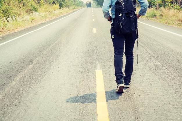 Seção baixa de caminhante com mochila caminhando na estrada