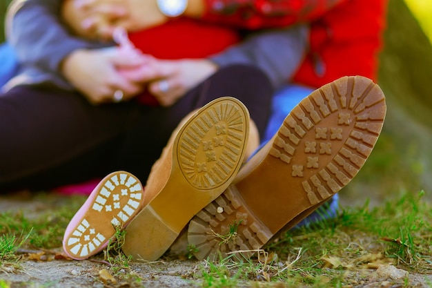 Foto seção baixa de casal usando sapatos enquanto está sentado no campo
