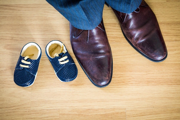 Foto seção baixa de homem e sapatos no chão de madeira dura