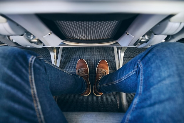 Foto seção baixa de homem vestindo jeans sentado em um avião