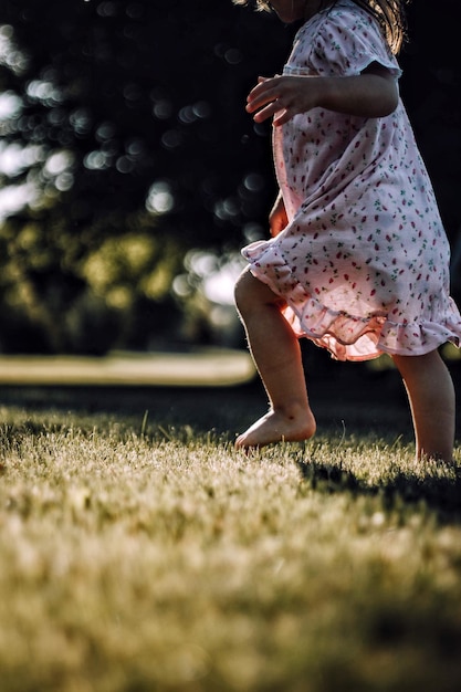 Seção baixa de menina caminhando em um campo gramado