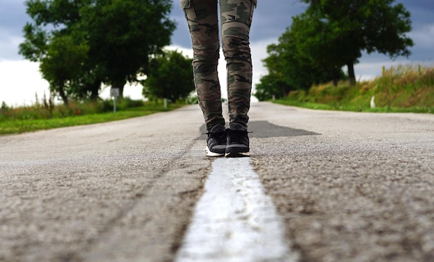 Seção baixa de mulher andando na estrada