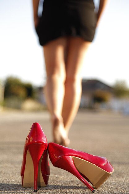 Foto seção baixa de mulher caminhando na rua com saltos altos