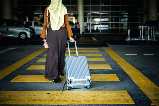 Seção baixa de mulher com bagagem caminhando no aeroporto