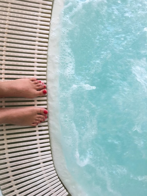 Foto seção baixa de mulher de pé à beira da piscina